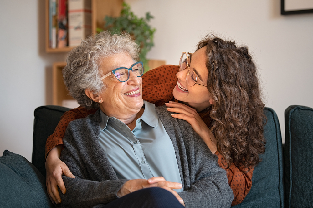 senior communities in marietta ga. A woman embraces her senior mother as they both smile.