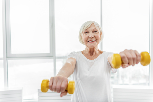 A senior woman works out with two small weights, senior living marietta ga